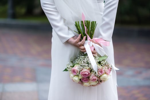 The bride in a white wedding dress is holding a bouquet of white flowers - peonies, roses. Wedding. Bride and groom. Delicate welcome bouquet. Beautiful decoration of weddings with leaves photo