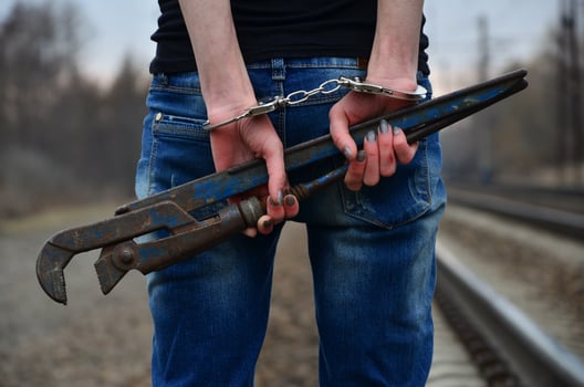 The girl in handcuffs with the pipe wrench on the railway track photo