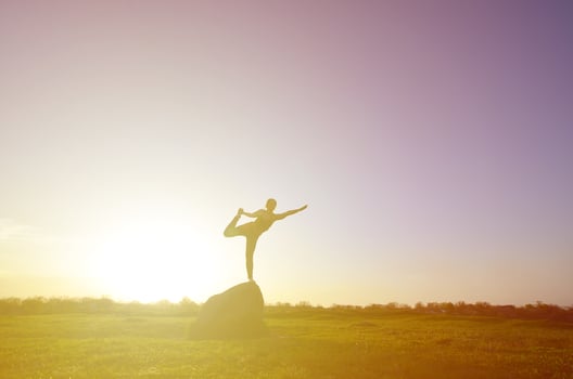 Silhouette of young blonde girl in sport suit practice yoga on a picturesque green hill in the evening at sunset. The concept of exercising and healthy lifestyles photo