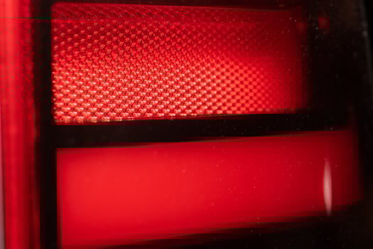 red background - detail of a red traffic warning lamp. The brake light assembly of a modern automobile photo