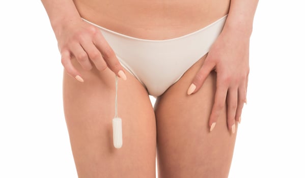 Female Period and Intimate Hygiene. Closeup cropped view of young woman in white panties holding tampon photo
