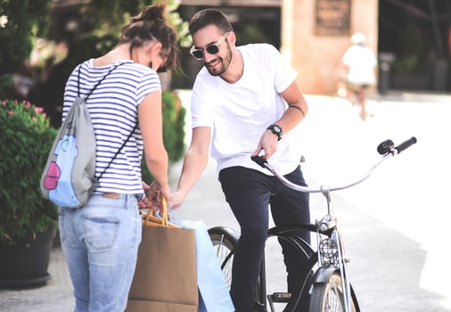 Portrait of cheerful Caucasian young couple man and woman holding many paper bags after shopping while walking and talking on street. Happy family couple with packages outdoor. Buying concept photo