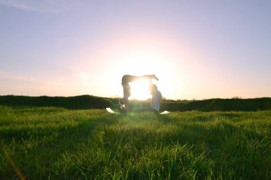 Young guy and girl in sports suits practice yoga on a picturesque green hill in the open air in the evening. The concept of practicing sports in pairs and a healthy lifestyle photo