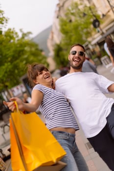 Portrait of cheerful Caucasian young couple man and woman holding many paper bags after shopping while walking and talking on street. Happy family couple with packages outdoor. Buying concept photo