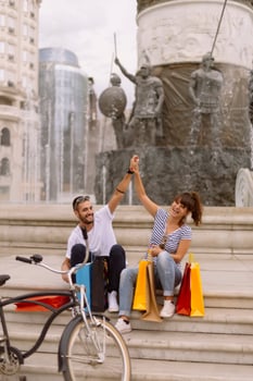 Portrait of cheerful Caucasian young couple man and woman holding many paper bags after shopping while walking and talking on street. Happy family couple with packages outdoor. Buying concept photo