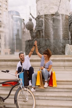 Portrait of cheerful Caucasian young couple man and woman holding many paper bags after shopping while walking and talking on street. Happy family couple with packages outdoor. Buying concept photo