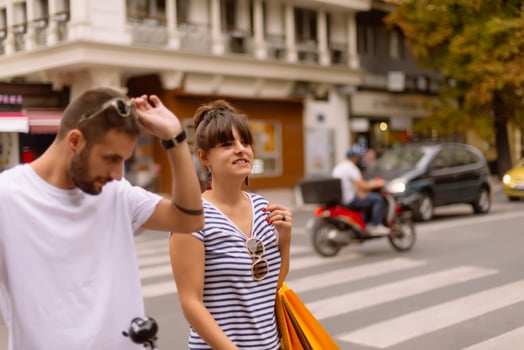 Portrait of cheerful Caucasian young couple man and woman holding many paper bags after shopping while walking and talking on street. Happy family couple with packages outdoor. Buying concept photo