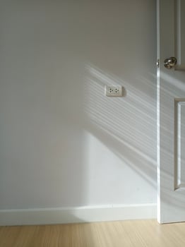 A vertical shot of a room playing with light and shadow coming in from the left window. It hits the walls and the light-colored doors. photo