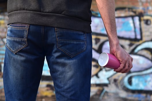 Graffiti artist with a spray can in his hand. Back view photo