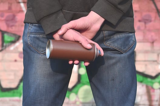 Graffiti artist with a spray can in his hand. Back view photo