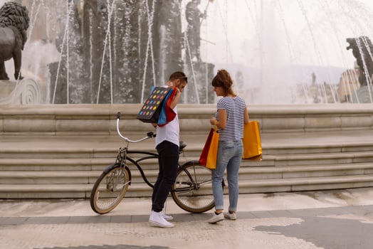 Portrait of cheerful Caucasian young couple man and woman holding many paper bags after shopping while walking and talking on street. Happy family couple with packages outdoor. Buying concept photo