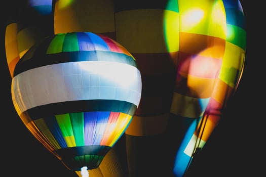 Close-up shot of bright and beautiful red, blue, yellow, and orange balloons rising in the night sky with a black background. photo