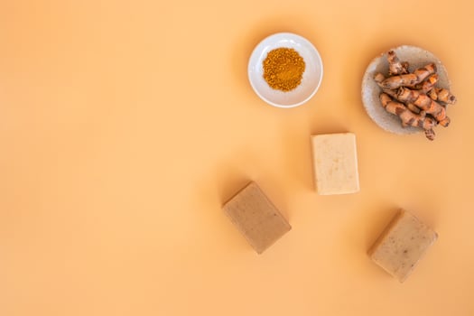 Top view of turmeric and bar soap on orange pastel background. Spa background concept. photo