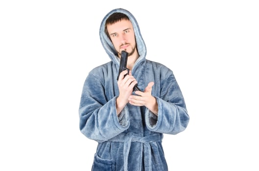 Portrait of young caucasian bearded man in blue bathrobe with black firearm isolated on white background photo