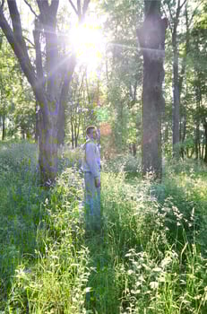 A young guy in a gray sports suit stands opposite the sun among photo