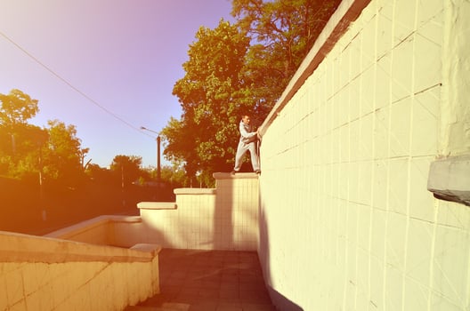 A young guy overcomes obstacles, climbing on concrete walls. The athlete practices parkour, training in street conditions. The concept of sports subcultures among youth photo