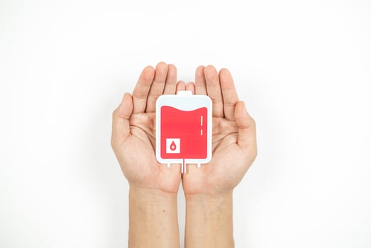 Hands holding blood pack paper cut on white background, Blood transfusion, World blood donor day. Blood Donation and Saving life Concept photo