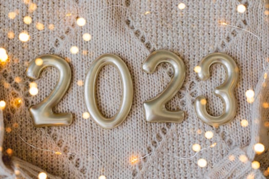 Numbers 2023 made of golden number on beige knitted sweater as background. Happy New Year 2022, Christmas, cozy holiday concepts. Top view, flat lay photo