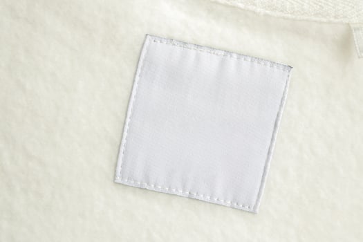 Blank white laundry care clothes label on fabric texture background photo