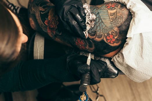 close up tattoo machine. Woman creating picture on hand with it in salon photo