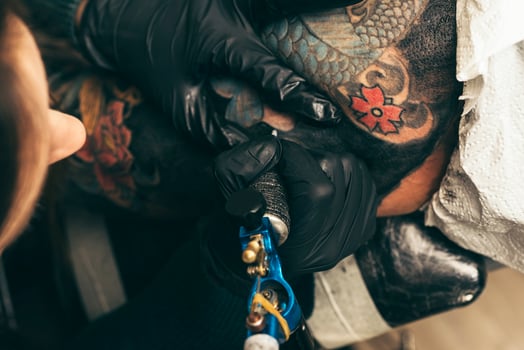 close up tattoo machine. Woman creating picture on hand with it in salon photo