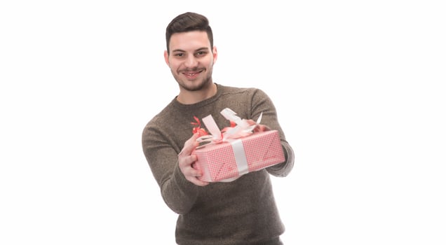 Young handsome man holding birthday present, looking positive and happy standing and smiling with a confident smile photo
