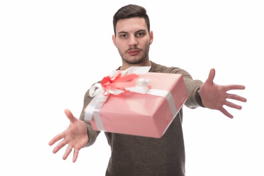 Young handsome man holding birthday present, looking positive and happy standing and smiling with a confident smile photo