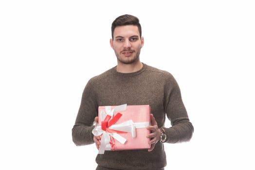 Young handsome man holding birthday present, looking positive and happy standing and smiling with a confident smile photo