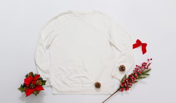 Close up white blank template sweatshirt copy space. Christmas Holiday concept. Top view mockup sweatshirt. Red holidays decorations on white background. Happy New Year accessories. Xmas outfit photo