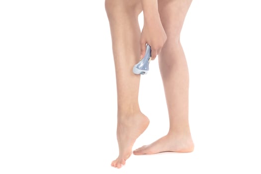 Shave legs electric epilator. Woman depilates her leg with an electric epilator device in the bathroom. Female shaves legs with white depilator. Removal hair. Close up, woman's leg shaving. photo