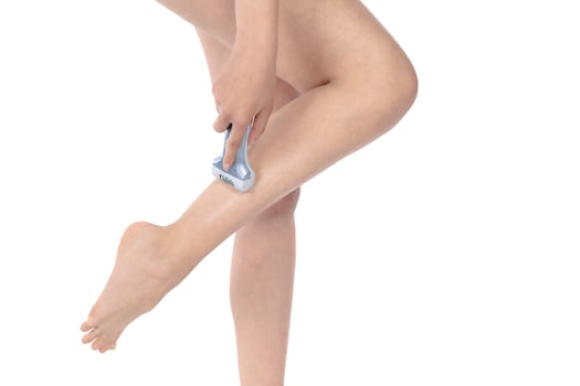 Shave legs electric epilator. Woman depilates her leg with an electric epilator device in the bathroom. Female shaves legs with white depilator. Removal hair. Close up, woman's leg shaving. photo