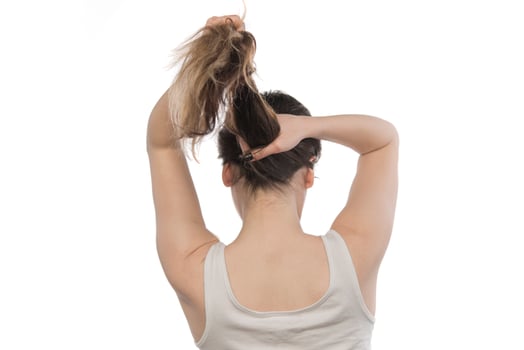 Female model arranging her hair. Woman tying hair in a bun. photo