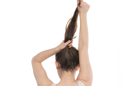 Female model arranging her hair. Woman tying hair in a bun. photo