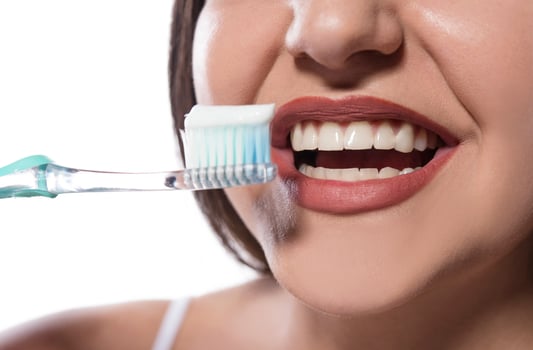 portrait of attractive smiling woman isolated on white studio shot brushing her teeth photo