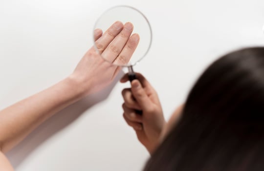 Woman looking her hand nails true magnifying glass. photo