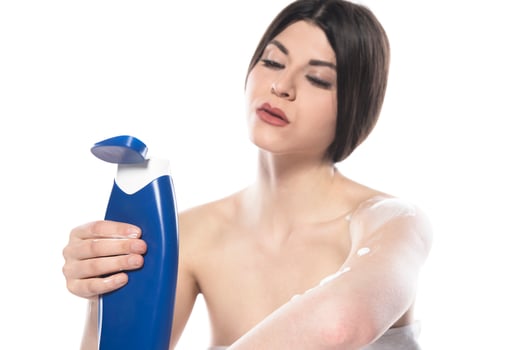 Beautiful skinned woman applying body lotion on white background photo