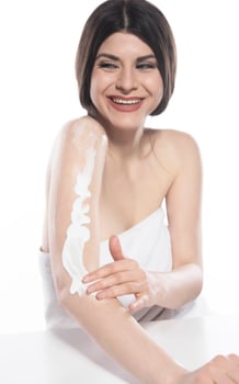 Beautiful skinned woman applying body lotion on white background photo