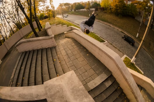 A young guy performs a side flip in the autumn park. The athlete practices parkour, training in street conditions. The concept of sports subcultures among youth photo