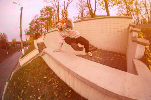 A young guy performs a jump through the concrete parapet. The athlete practices parkour, training in street conditions. The concept of sports subcultures among youth photo