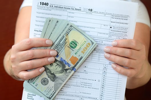 The girl holds in her hands the tax form and a large number of dollar bills photo