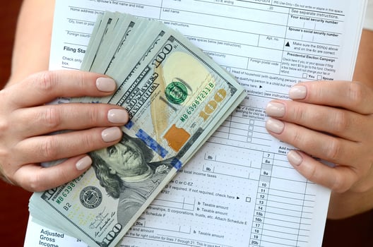 The girl holds in her hands the tax form and a large number of dollar bills photo