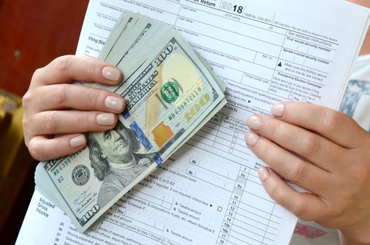 The girl holds in her hands the tax form and a large number of dollar bills photo