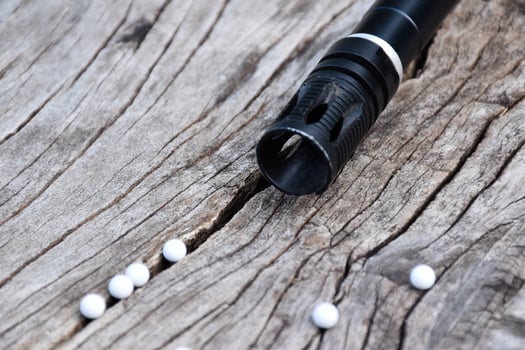 BB gun or airsoft gun muzzle and white bullets on wooden plank, soft and selective focus. photo