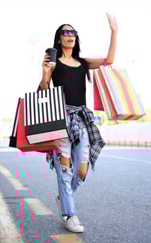 Beautiful woman walking on the street with shopping bags. Trendy female model in the city holdingshopping bags. photo