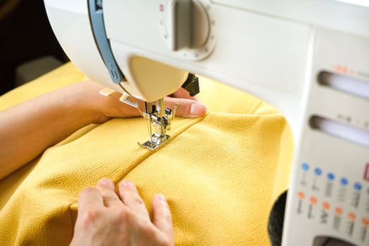 Female hands stitching yellow fabric on modern sewing machine. Close up view of sewing process. photo
