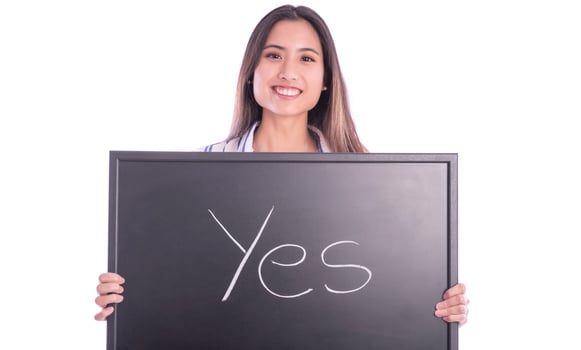 Beautiful Asian female model pointing on wedding ring on her hand and holding blackboard with YES sign on it. photo