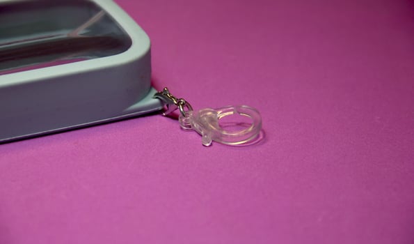 Transparent small object hook ring isolated on pinkish purple colored background for carrying portable hand sanitizer. photo