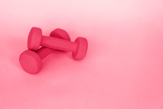 Green dumbbells for sports on a pink background. Sports, sports nutrition, healthy eating, diet. Space for the text. photo
