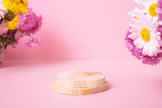 Wooden podium or pedestal with chrysanthemum flowers on pink background. Mockup for your cosmetic products photo