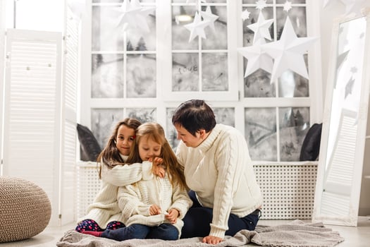 Merry Christmas and Happy Holidays. Cheerful mom and her cute daughters girls exchanging gifts. Parent and two little children having fun and playing together near Christmas tree indoors. photo